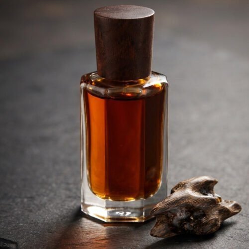 OudRaqy premium oud attar perfume oil bottle with agarwood chip on dark slate